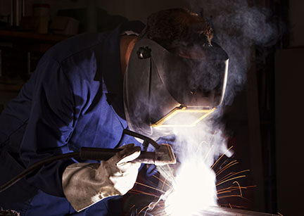 Worker welding in workshop.